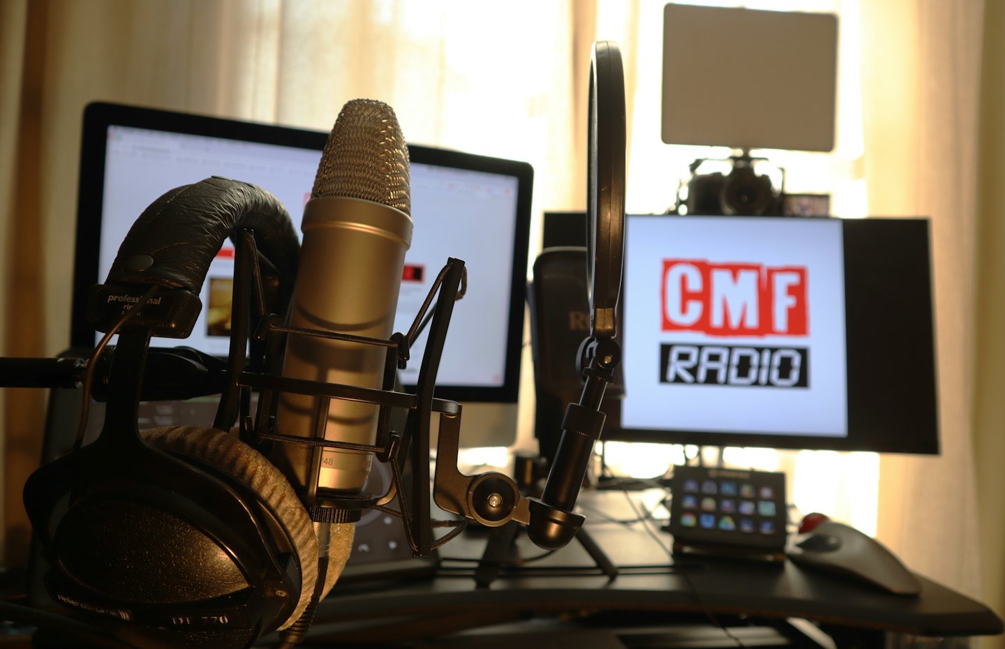 Podcasting microphone with pop filter and headphones on a desk.